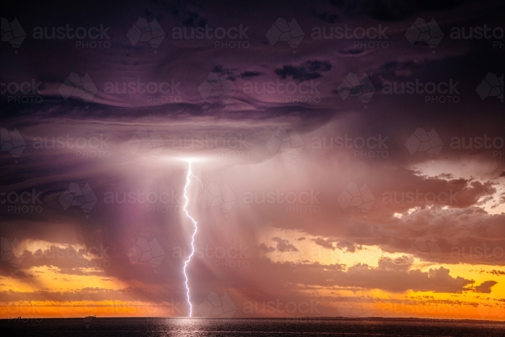 Sunset lightning bolt and stormy sky over the ocean - Australian Stock Image