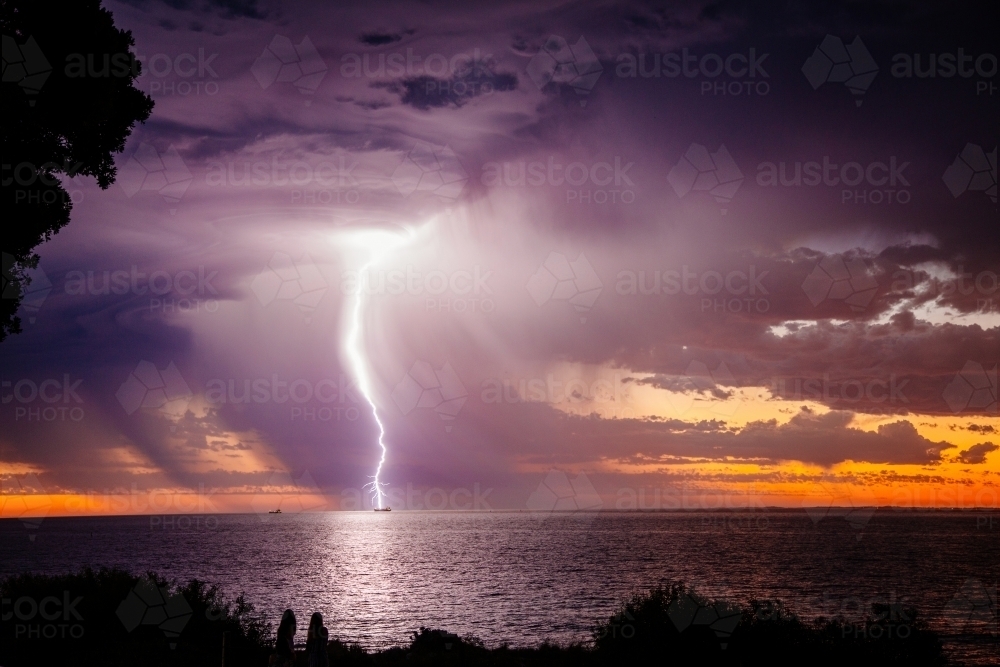 Sunset lightning bolt and stormy sky over the ocean - Australian Stock Image