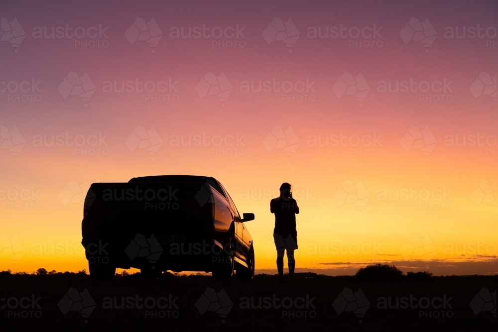 Sunset silhouette of man and car - Australian Stock Image