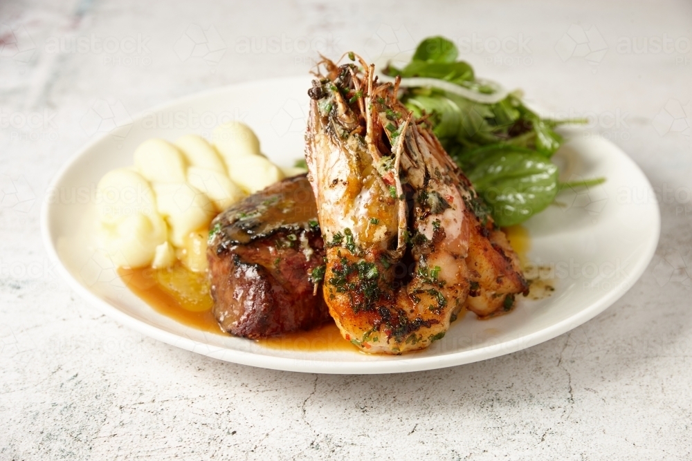 Surf and Turf - a steak and grilled prawns served with salad and mash - Australian Stock Image