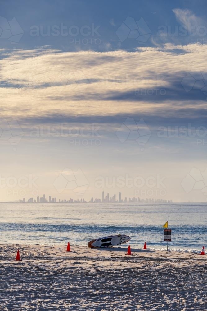 Surf Life Saving board on beach with city in background - Australian Stock Image