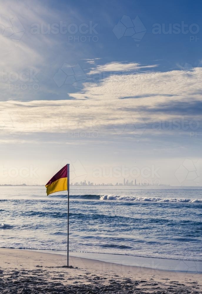 Surf Life Saving flag on beach with city in background - Australian Stock Image