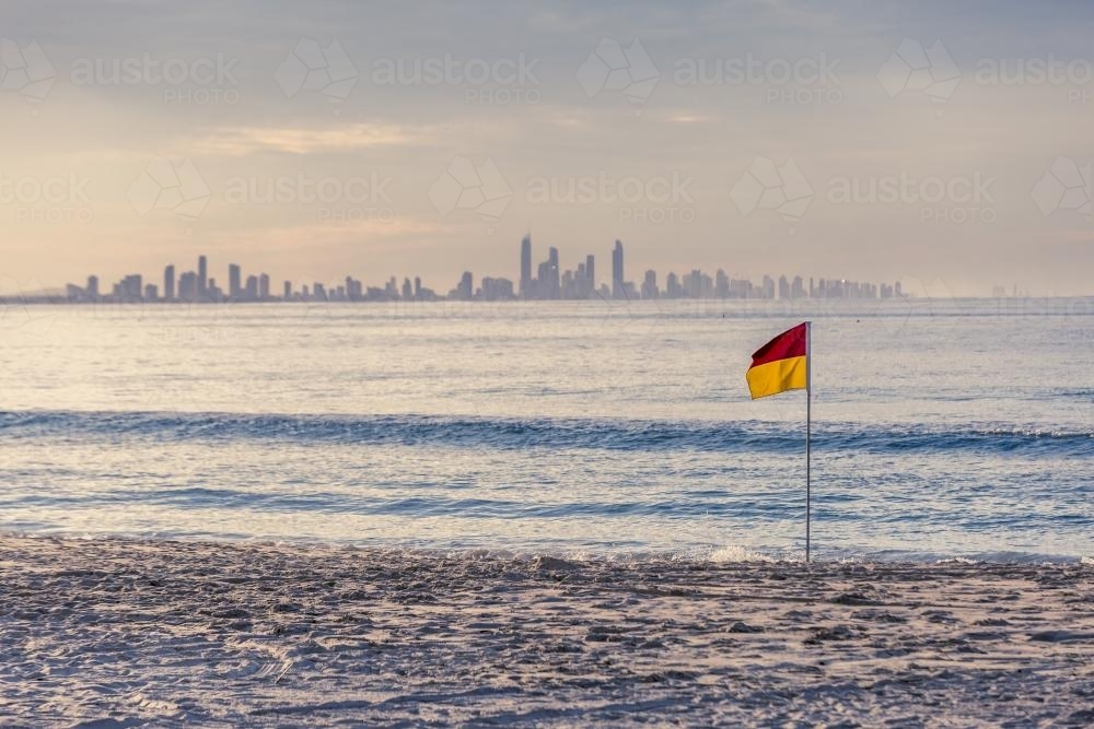 Surf Life Saving patrol flag on beach with city in background - Australian Stock Image