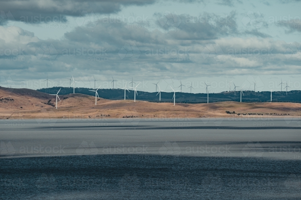 Sustainable energy wind turbines on the rolling hills behind Lake George. - Australian Stock Image
