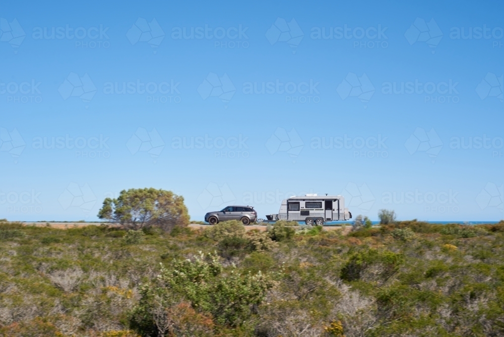 SUV with a caravan driving along a coastal road in Western Australia on a road trip. - Australian Stock Image