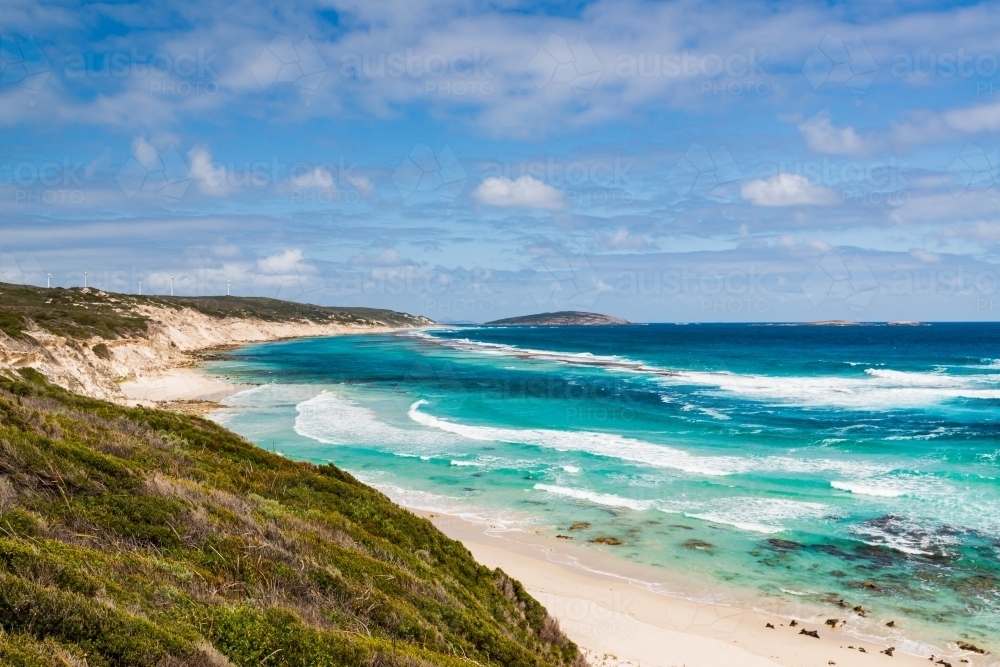 Sweeping coastal view  with wind turbines above sand dunes and colourful ocean - Australian Stock Image