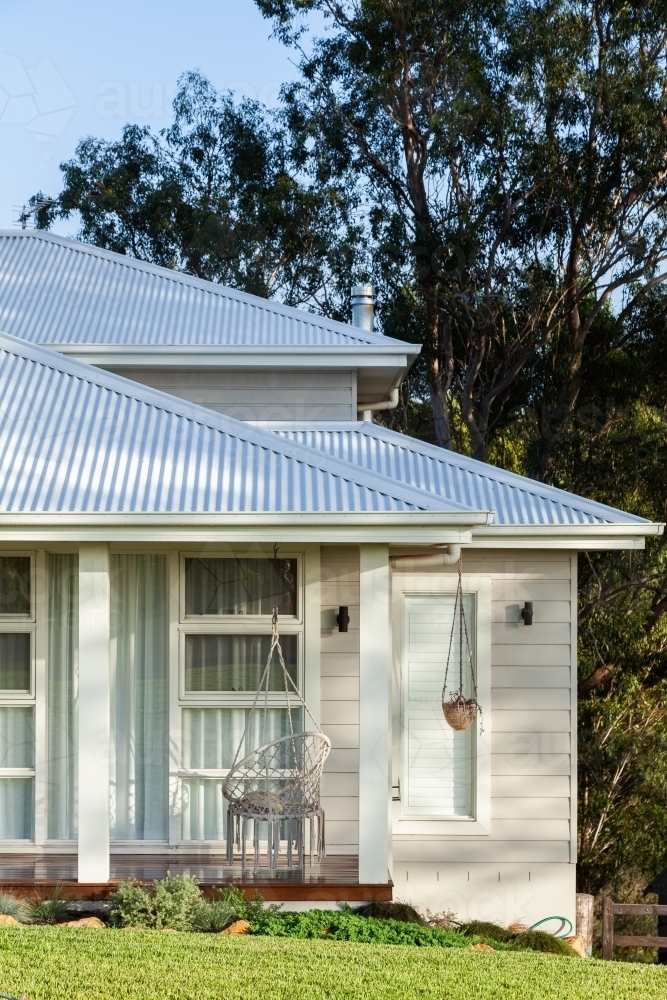 Swinging chair on house verandah in quiet country setting on the edge of town - Australian Stock Image