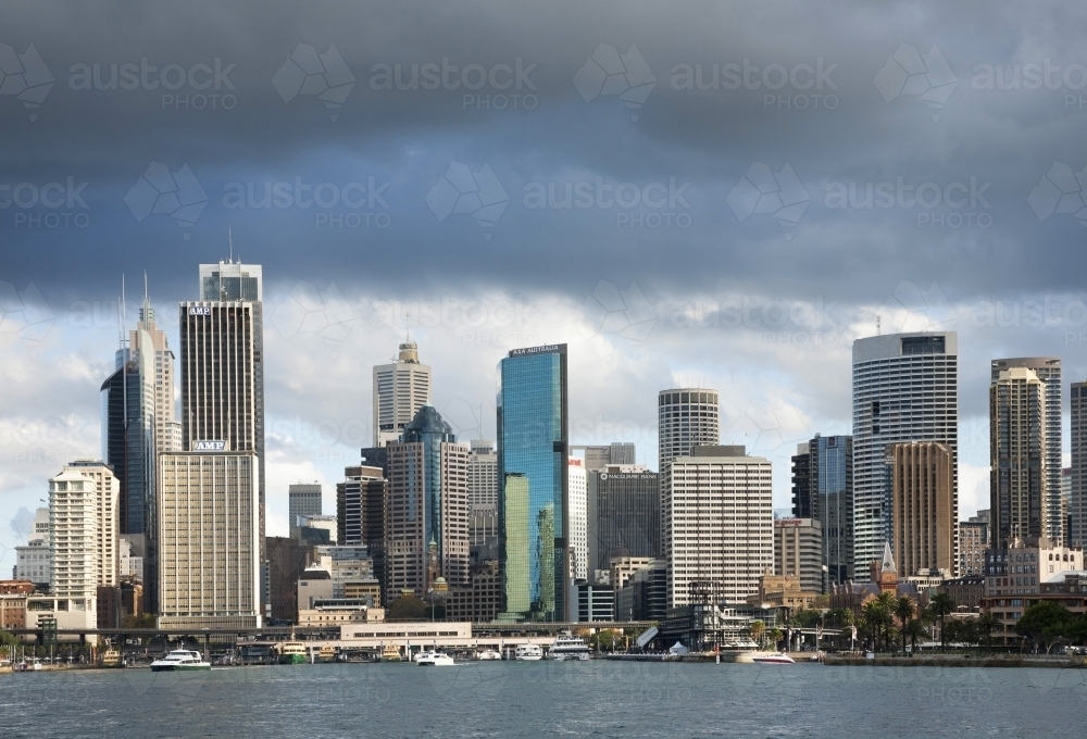 Sydney CBD from Sydney Harbour with tall buildings and dark clouds - Australian Stock Image