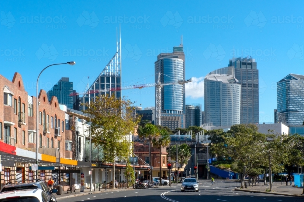 Sydney city skyline from Woolloomooloo with road and shops in foreground - Australian Stock Image