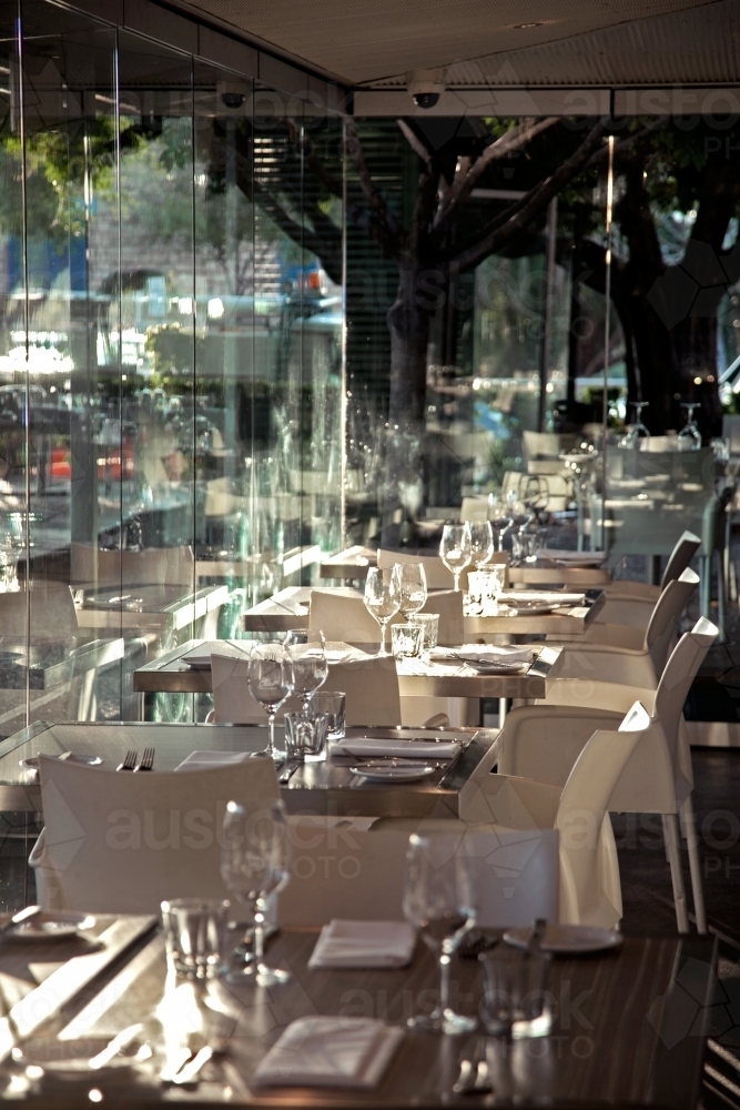 Table settings inside a restaurant with glass walls - Australian Stock Image