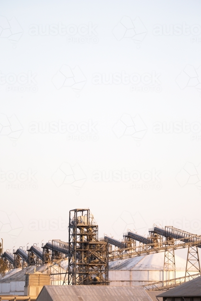 tall steel tower with metal works around it and silos under big sky - Australian Stock Image