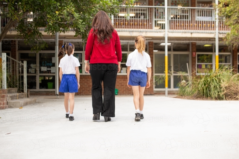 Teacher and Two Students Walking Away from Camera - Australian Stock Image