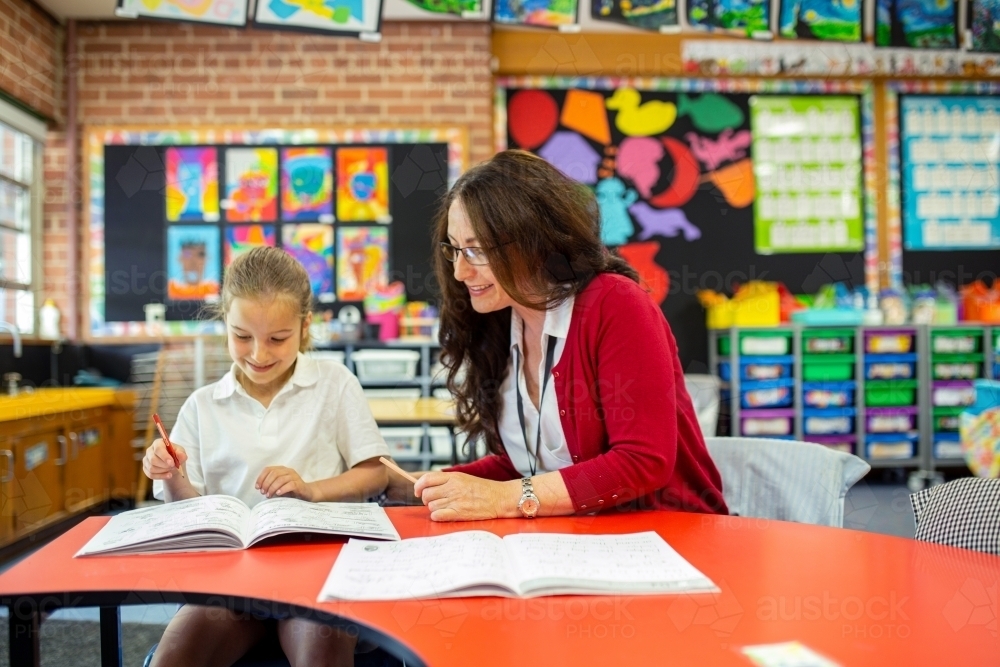 Teacher Helping Young Student in Classroom - Australian Stock Image