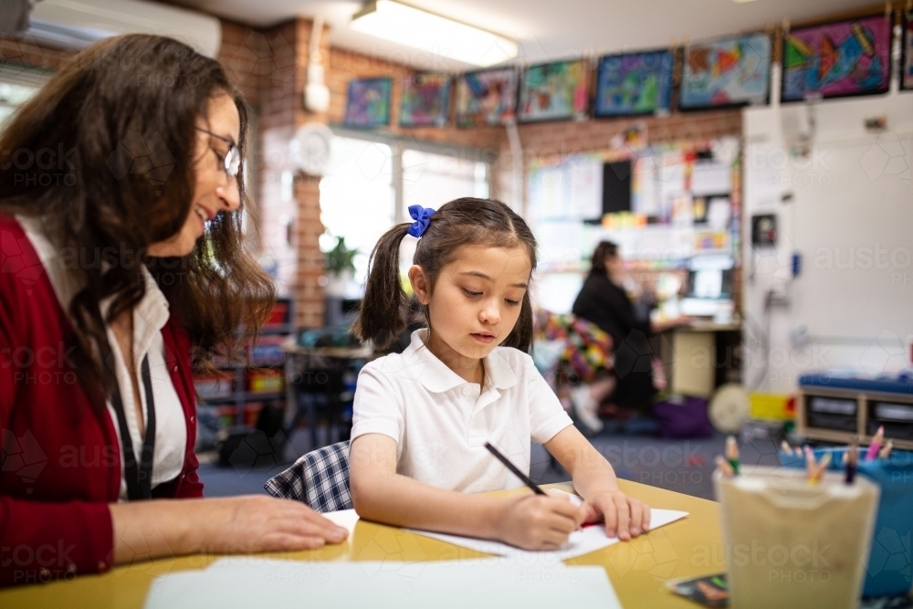 Teachers aid and Student Writing in Classroom - Australian Stock Image