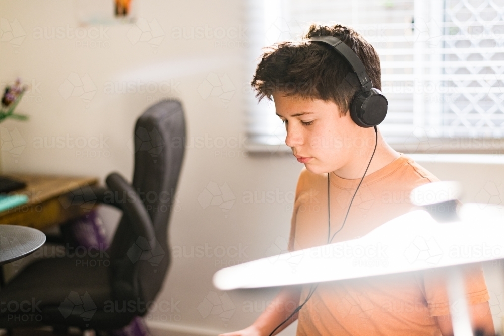 teen boy practising drums at home - Australian Stock Image