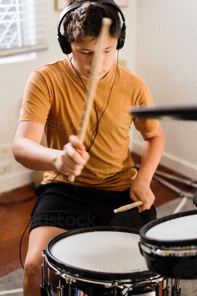 teen boy practising drums at home - Australian Stock Image