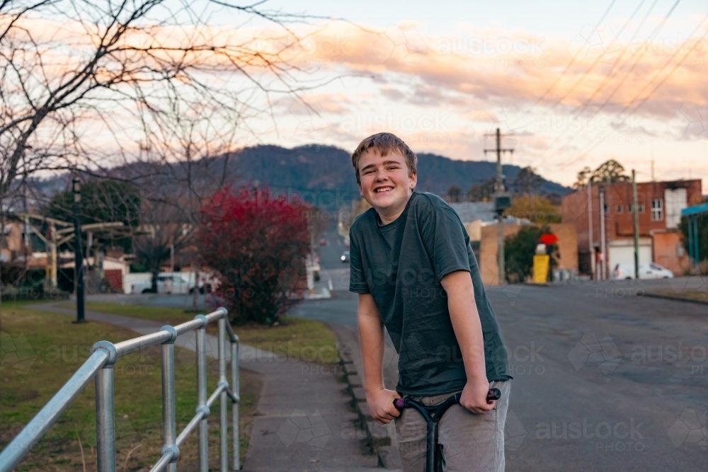 Teen boy riding scooter in country town - Australian Stock Image