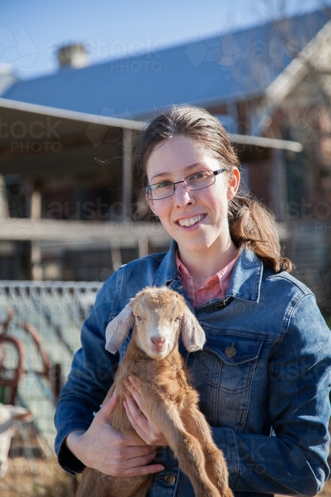 Teen girl holding baby goat on a farm - Australian Stock Image