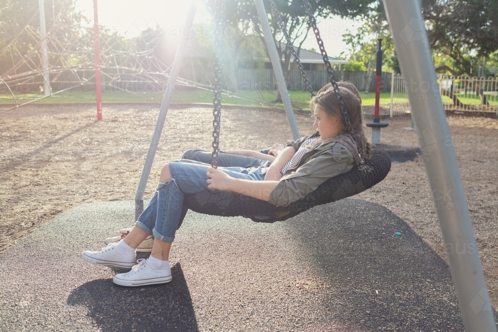 Teen girl on big swing with friend - Australian Stock Image