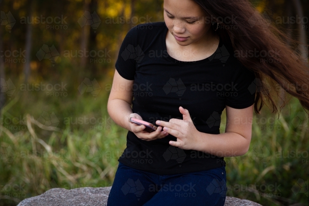 Teen girl reading a phone - Australian Stock Image