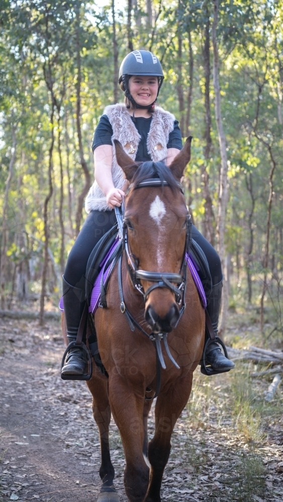 Teen girl riding her horse through the bush - Australian Stock Image