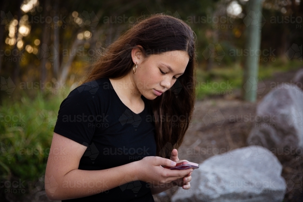 teen girl scrolling on her phone - Australian Stock Image