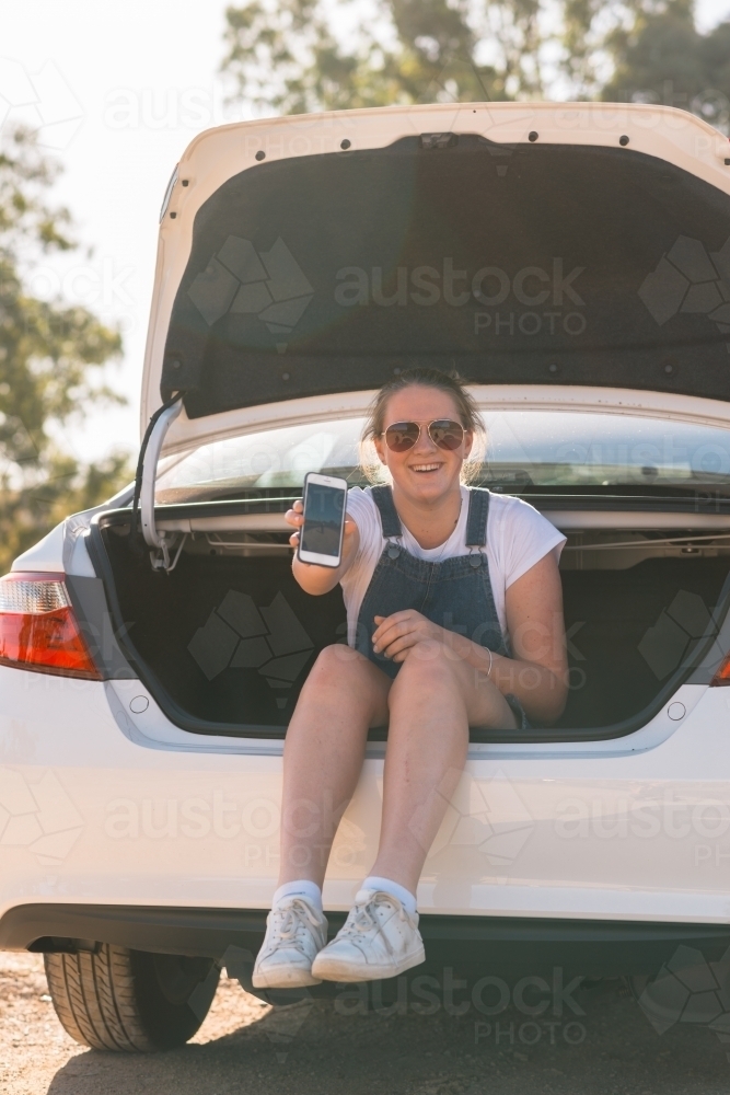 teen girl sitting in boot of car on a road trip - Australian Stock Image