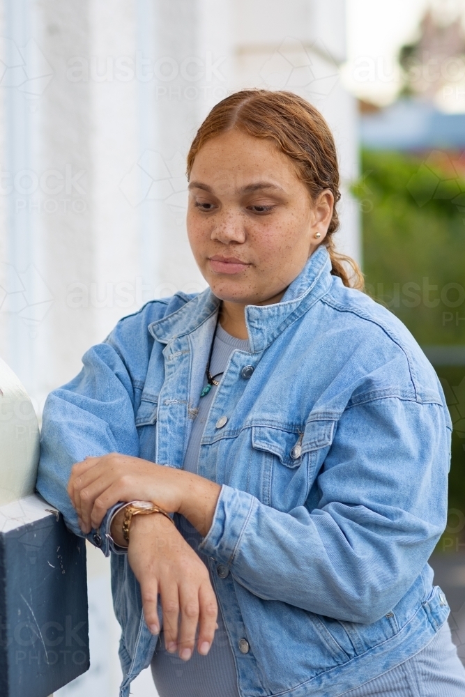 teen girl with downcast eyes wearing denim jacket - Australian Stock Image