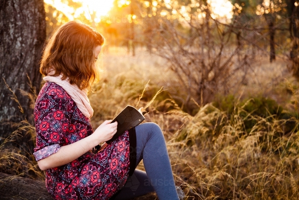 Teen girl with notebook and short hair at sunset - Australian Stock Image