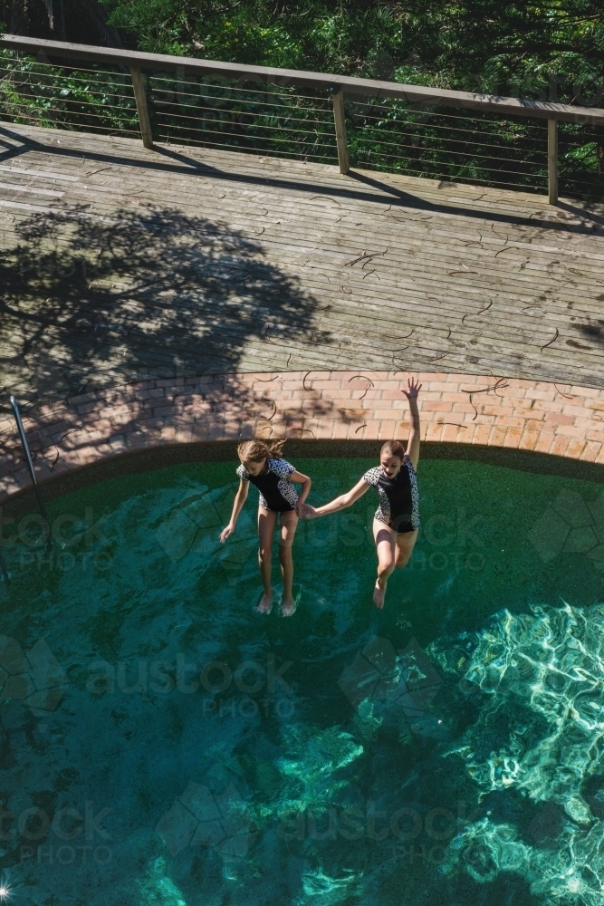 teen girls jumping in a swimming pool - Australian Stock Image