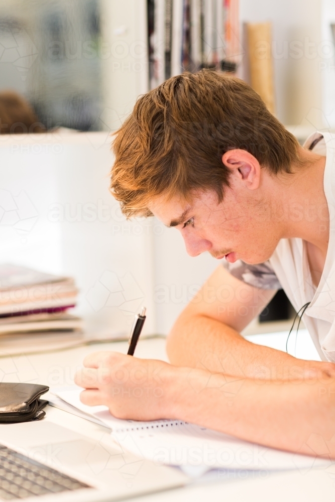 Teenage boy studying at desk - Australian Stock Image