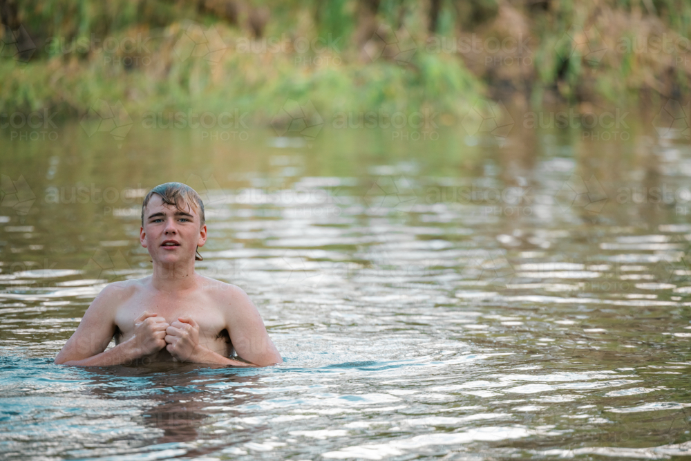 Teenage boy swimming in river on summer day - Australian Stock Image