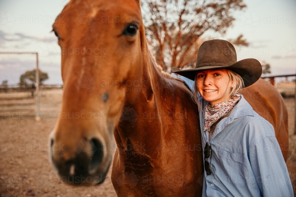 Teenage female smiling beside brown horse looking at camera - Australian Stock Image