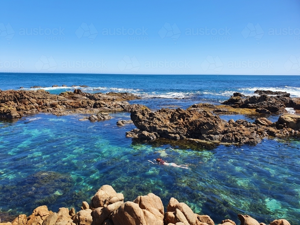 Teenage girl floating in an ocean rock pool - Australian Stock Image