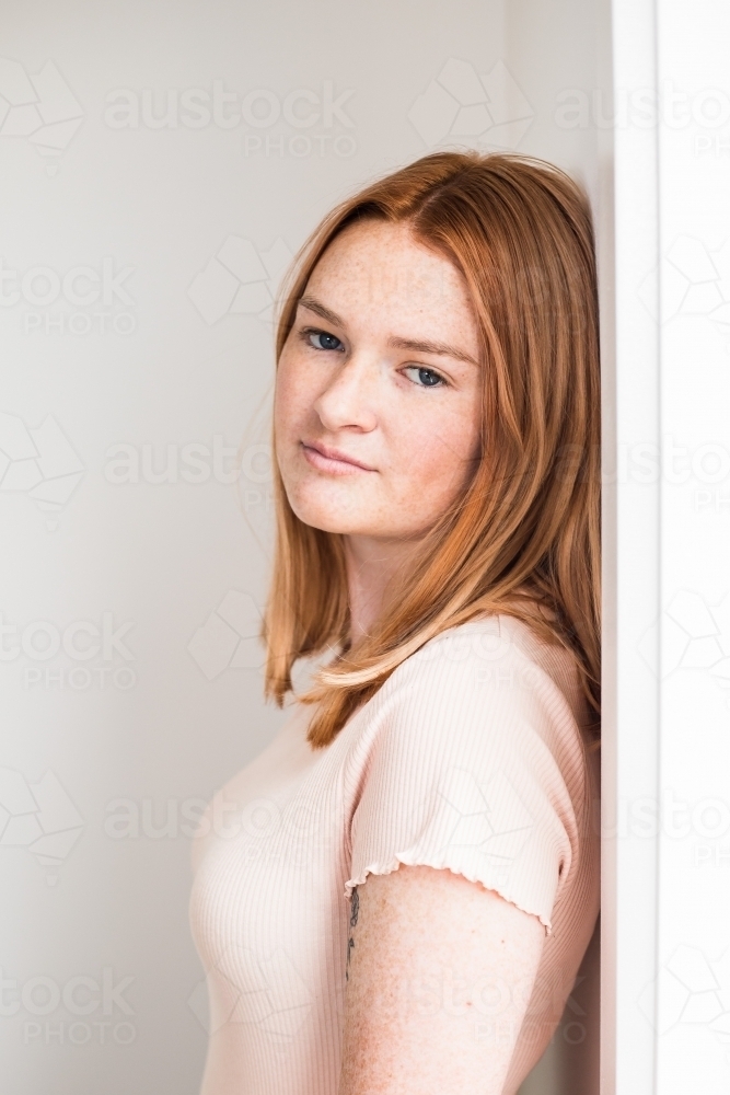 Teenage girl leaning against frame with small smile - Australian Stock Image