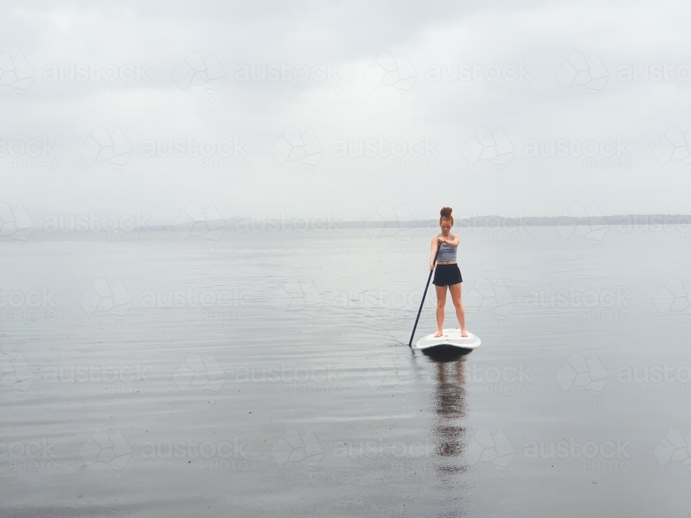 Teenage girl on a stand up paddle board - Australian Stock Image