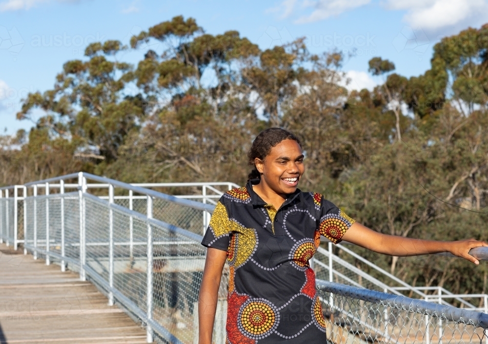 teenage girl on overpass walkway wearing aboriginal design shirt - Australian Stock Image