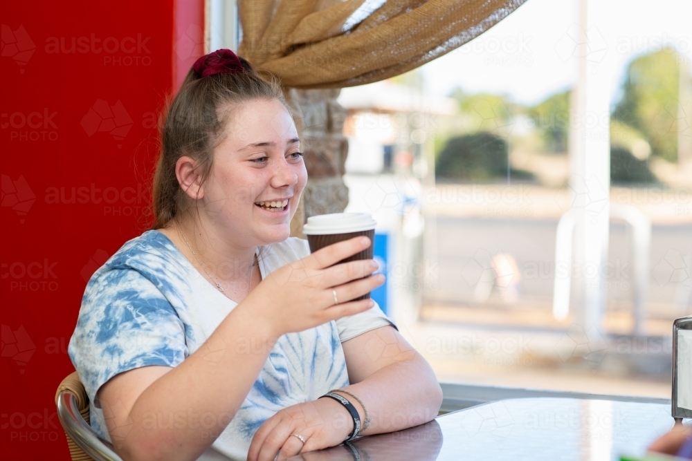 Teenage girl sitting at table with coffee - Australian Stock Image