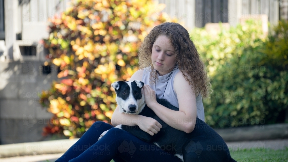 Teenage girl sitting with her dog - Australian Stock Image