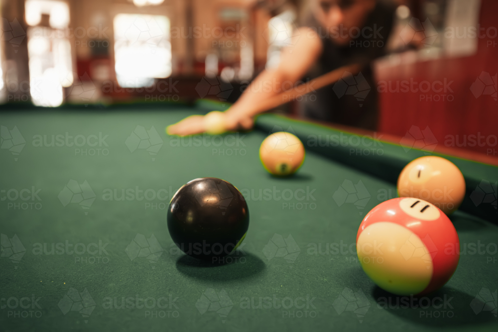 Teenage male playing 8 ball pool on billiard table in Australian pub - Australian Stock Image