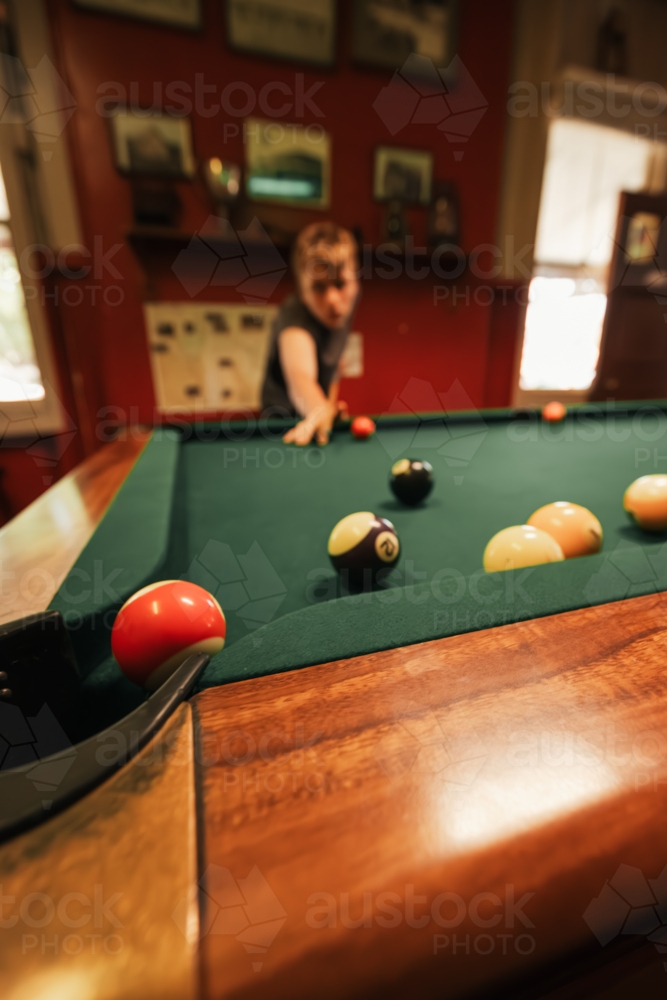 Teenage male playing 8 ball pool on billiard table in Australian pub - Australian Stock Image