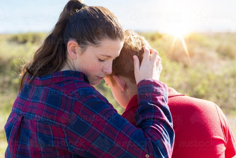 Teenager girl holding boy close - Australian Stock Image