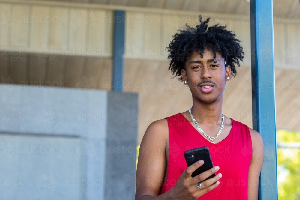 teenager holding smartphone looking at camera - Australian Stock Image