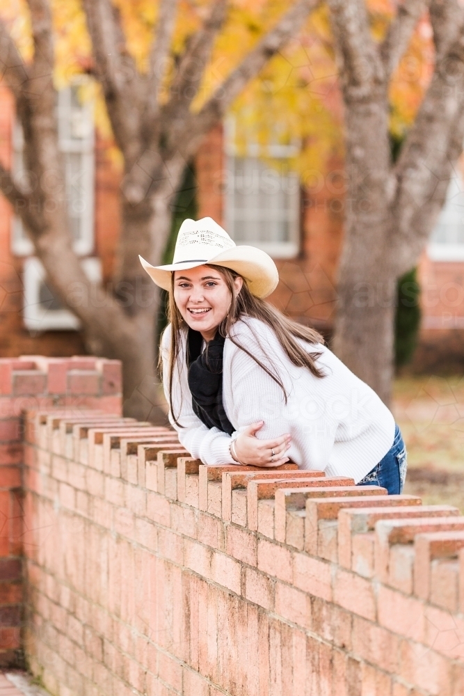 Teenager leaning forward on brick wall laughing - Australian Stock Image