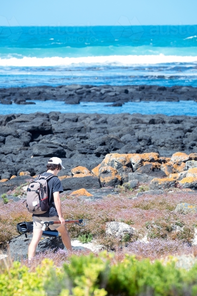 Teenager walks across the rocks to go snorkeling - Australian Stock Image