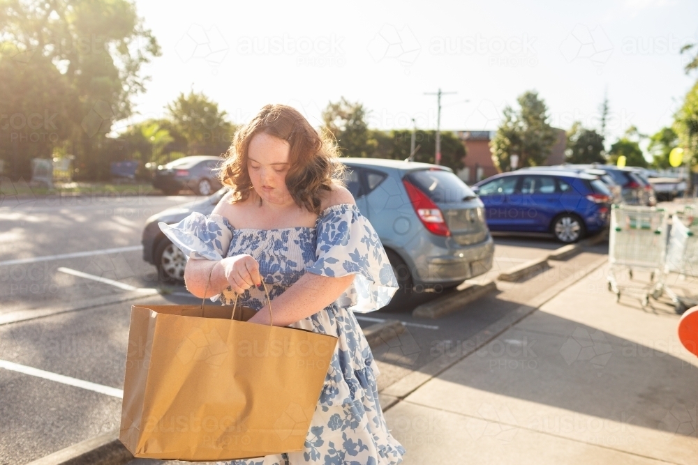 Teenager with down syndrome in community shopping with brown paper bag - Australian Stock Image