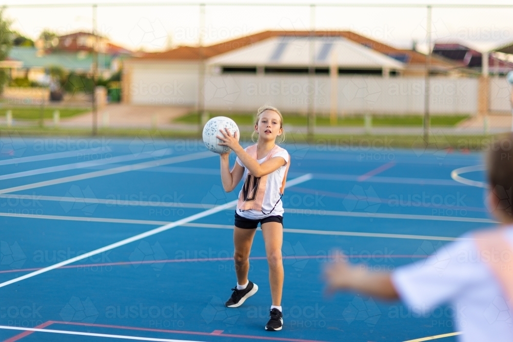 ten year old girl ready to throw netball to teammate at training - Australian Stock Image