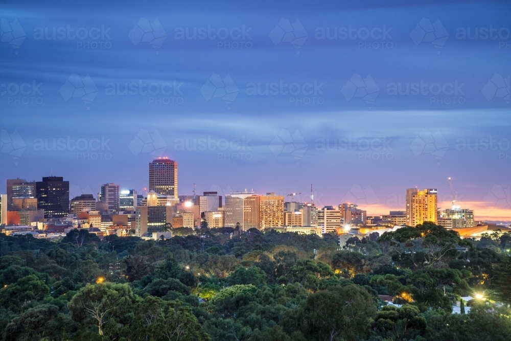 The Adelaide skyline at twilight viewed over from a distance over gumtrees - Australian Stock Image