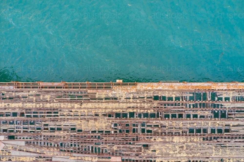 The contrast of a derelict jetty falling to pieces and the crystal clear turquoise ocean water. - Australian Stock Image