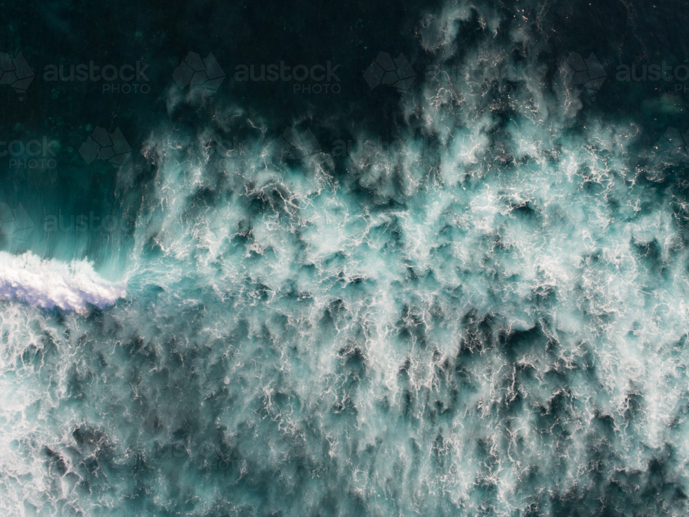 The dark ocean displays an abstract patterns after a crashing wave - Australian Stock Image